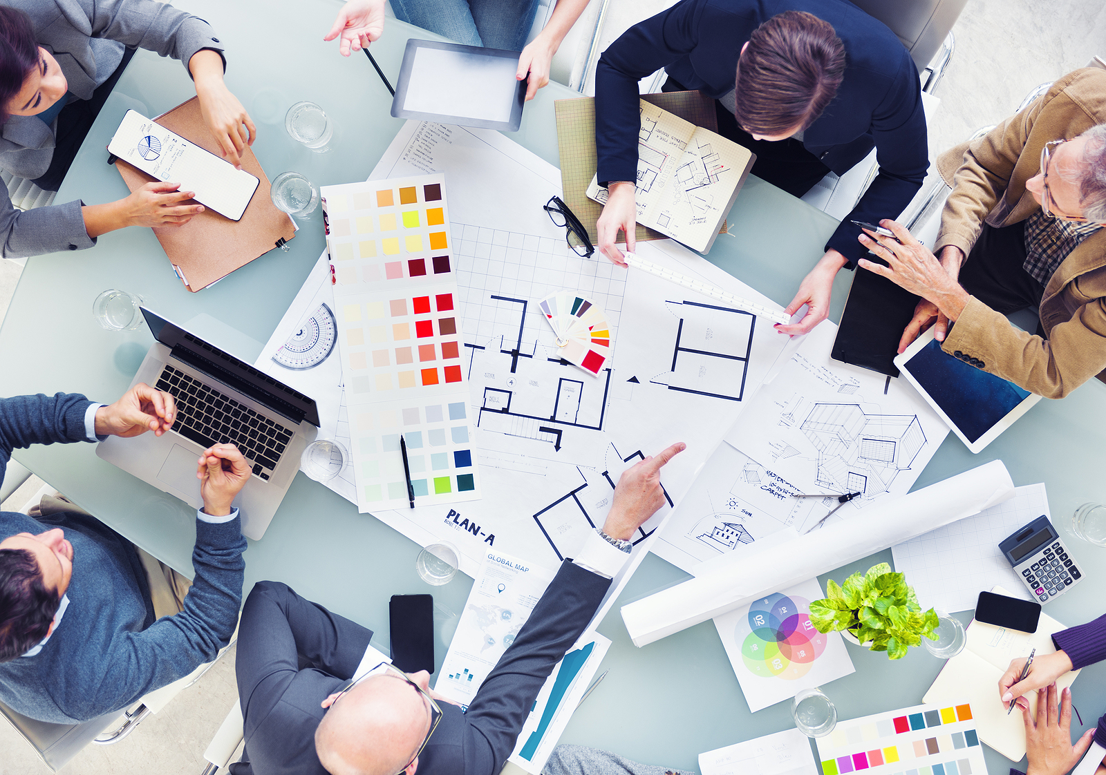 Luxury home design team with Architect, Interior designer, General Contractor and Technology Consultant. Blue prints layed out on table with color swatches laid out